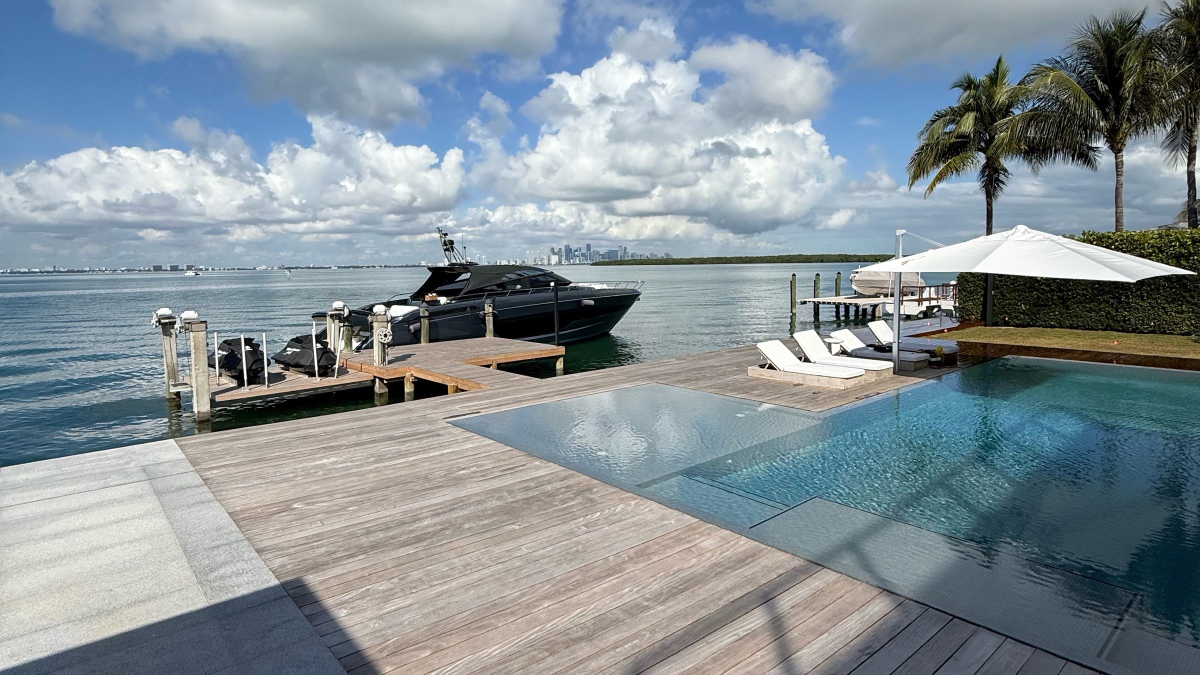 A Riva 68 Diable at a private dock on Biscayne Bay, teak deck and infinity pool, Miami skyline on the horizon